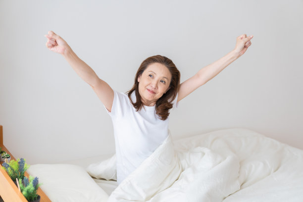 穿着睡衣躺在床上的老年妇女，微笑图片下载