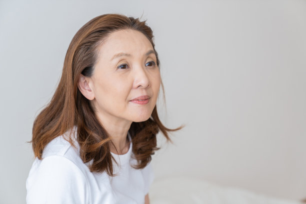 穿着睡衣躺在床上的老年妇女，微笑图片下载