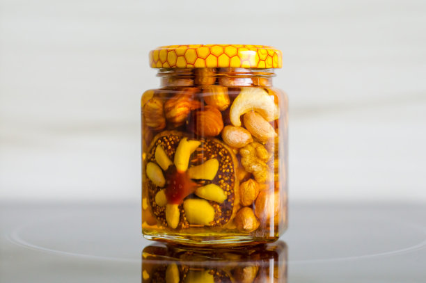 蜂蜜和坚果放在玻璃表面的罐子里，孤立图片下载
