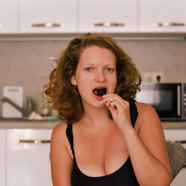 一个年轻的女人在厨房里吃樱桃图片下载