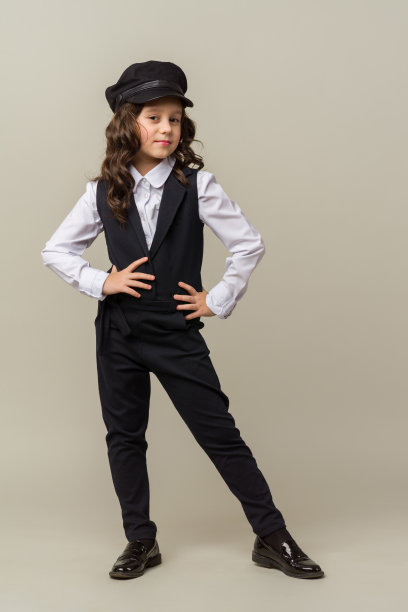 美丽的小女孩站在灰色的背景和姿势图片下载