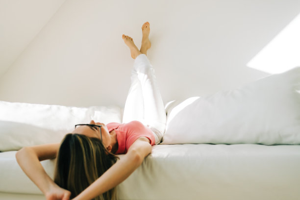 年轻的白人妇女放松在沙发上明亮的客厅。图片下载