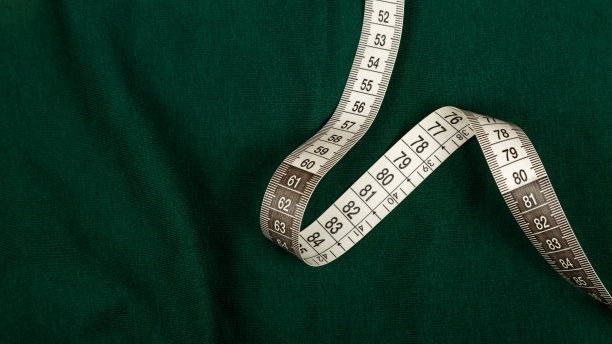 厘米胶带，健身和减肥。绿色背景上的裁缝尺，用于缝纫。米，卷尺，用来测量身体，腰围以厘米为单位。图片下载