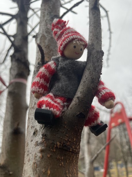 由天然有机材料制成的微笑的圣诞精灵小玩具，雨天坐在树上图片下载