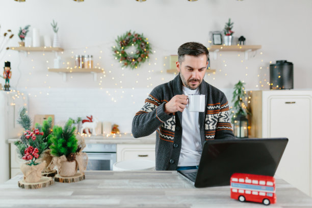 一名男性自由商人在圣诞节假期期间完成一个在最后期限内完成的项目，在家厨房工作图片下载