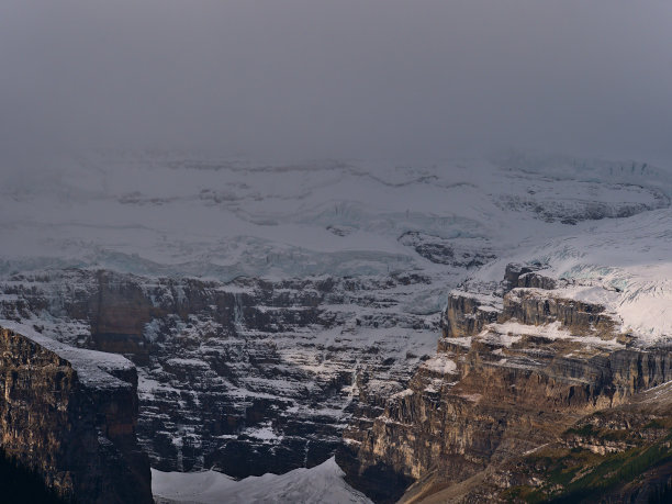 加拿大阿尔伯塔省班夫国家公园崎岖的维多利亚峰的特写照片，是落基山脉的一部分，与维多利亚冰川一起消失在云层中。图片下载