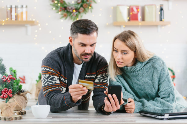 年轻幸福的家庭在新年和圣诞假期期间在家里快乐地购买礼物使用智能手机和信用卡图片下载