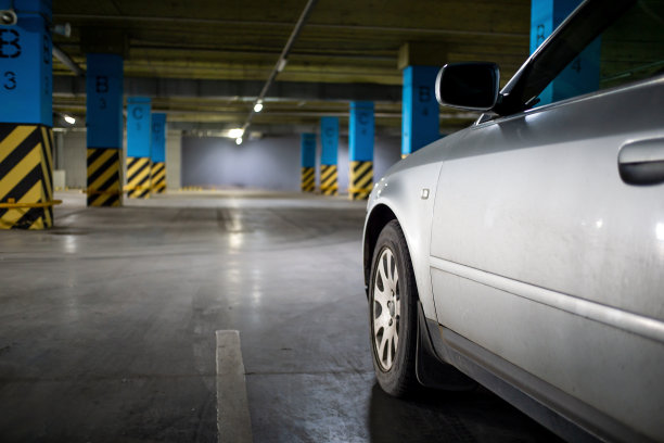 空的地下停车场。一辆银色的车停在空荡荡的停车场，远景。现代停车场的混凝土地板。图片下载