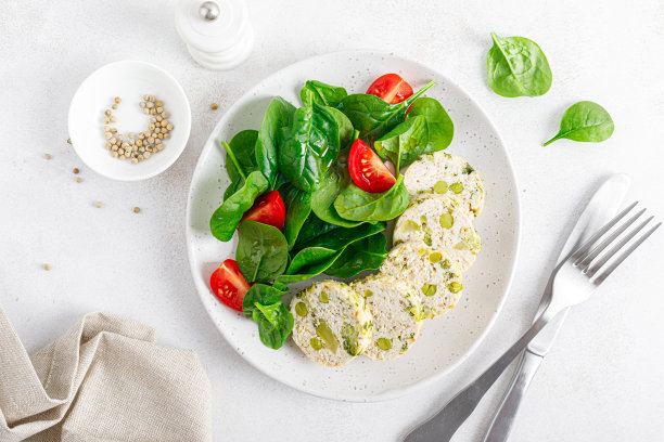 鸡冻肉卷。填充肉，花椰菜肉饼，青豆和新鲜菠菜番茄沙拉。前视图。图片下载
