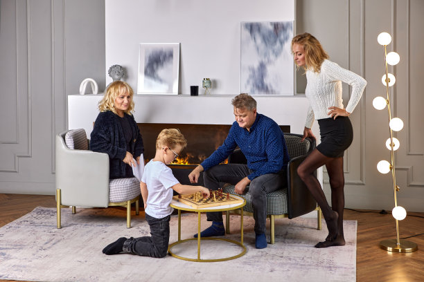 茶几上，小孙子在奶奶和妈妈的监督下和爷爷下棋。图片下载