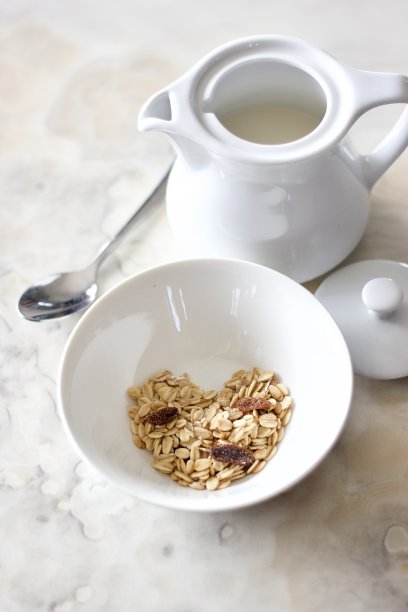 简单的早餐套装照片，白色的碗里有一个心形的什锦早餐，牛奶罐和勺子放在大理石地板上，这是简单早餐的概念图片下载