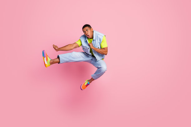 愤怒的千禧一代深色男子打架的全长照片穿t恤背心牛仔裤现代彩色运动鞋孤立的粉红色背景图片下载