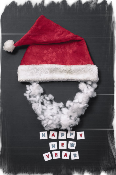 在深灰色图案的背景上，红色天鹅绒圣诞帽和彩色字母题词新年快乐图片下载