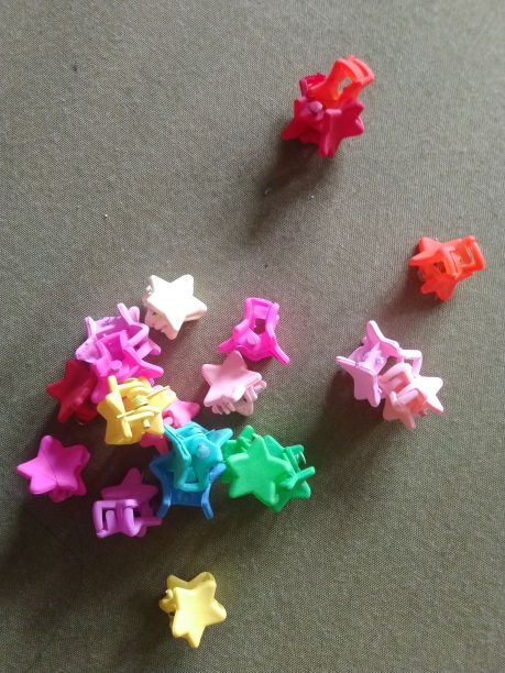 绿色布上星星形状的可爱的彩色小发夹图片下载