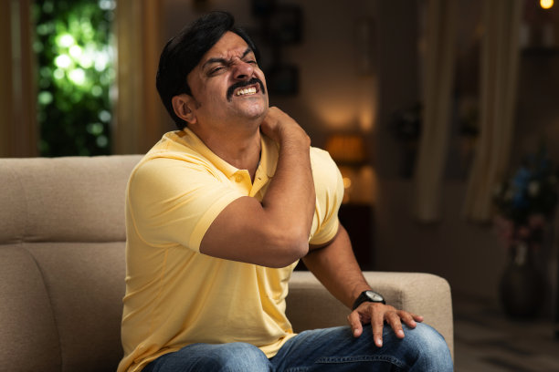 不开心的男人遭受脖子或肩膀疼痛在家里股票照片图片下载