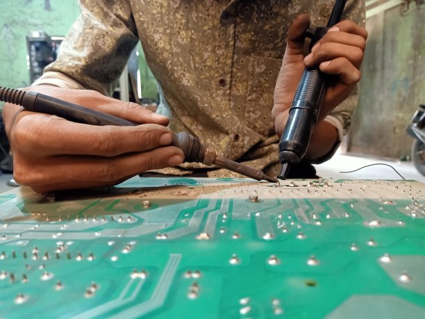 工程师在线维护UPS主板。一位工程师在主板上使用烙铁。选择性对焦，背景模糊。图片下载