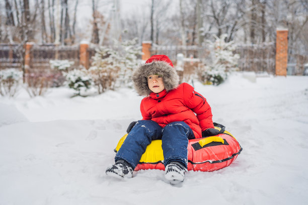孩子在雪地上玩得很开心。男孩骑着一根管子。孩子们的冬季乐趣图片下载