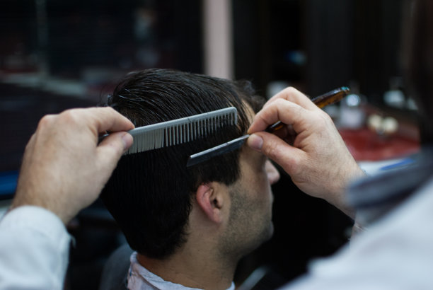 理发师的手为一个男人梳理和修剪头发的特写图片下载