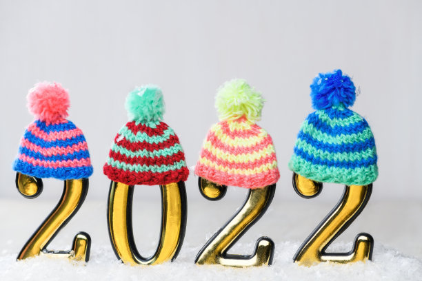 2022金色数字与多色针织帽子在白色背景与雪。新的一年是2022年图片下载