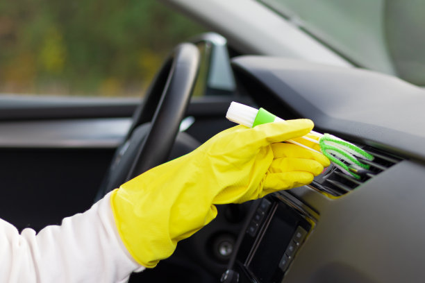 一个秋高气爽的日子，一只戴着黄色橡胶手套的手用特制的刷子擦拭着汽车仪表盘上的灰尘。有选择性的重点图片下载