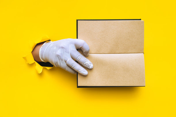 医生的手戴着白色乳胶医用手套，手里拿着黄色背景上的手工笔记本。撕碎的纸，有复印的空间，模仿。文本放置的概念。图片下载