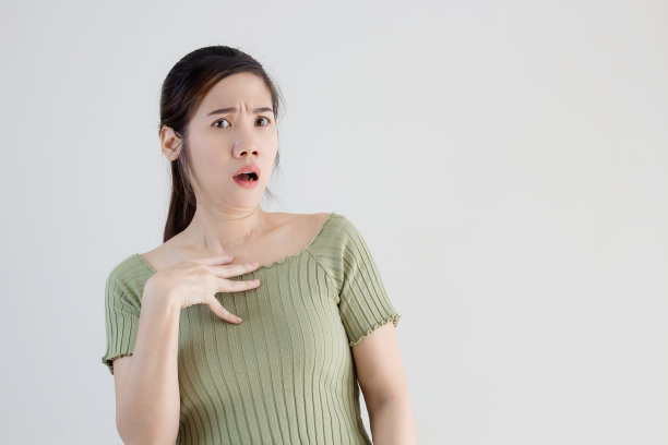 亚洲美女穿着绿色的t恤，当得到好消息和坏消息或信息或晋升时，用手摸着自己的胸部，脸上带着震惊和惊讶的表情图片下载