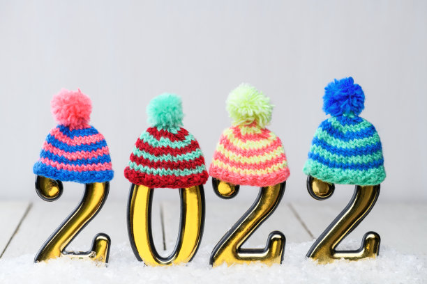 2022金色数字与多色针织帽子在白色背景与雪。新的一年是2022年图片下载
