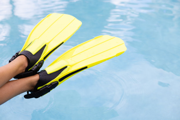 女性的腿在鳍在蓝色的水背景。暑假的概念。图片下载