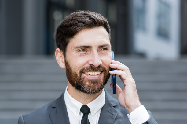 成功的大胡子商人微笑着打电话的特写照片图片下载