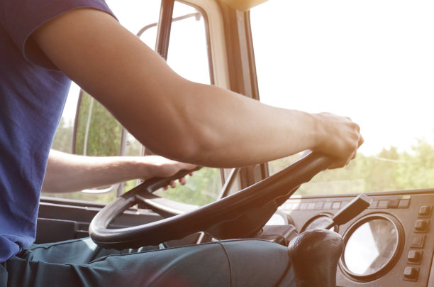 司机用双手握住卡车的方向盘。图片下载