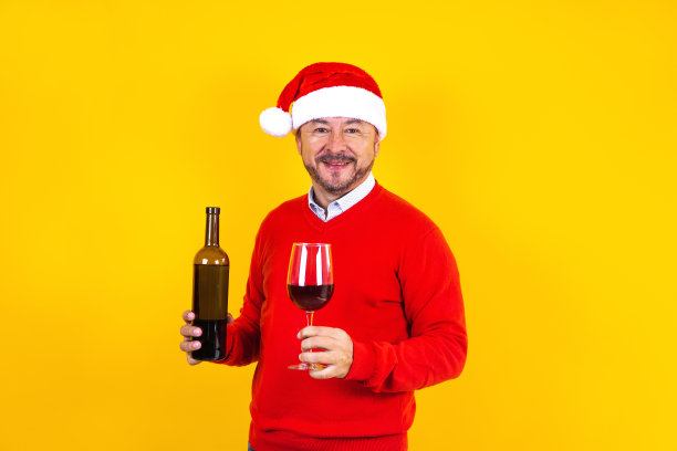 拉丁美洲，墨西哥，拉丁美洲，圣诞概念中的拉丁长者拿着一杯葡萄酒，戴着圣诞帽，开心地笑着图片下载
