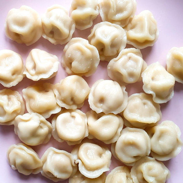 准备好的肉馅饺子，自制的俄罗斯佩尔梅尼放在粉红色的盘子里。俯视图，方形照片。图片下载