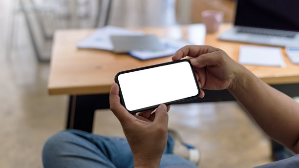 男子手持智能手机的近景空白的白色屏幕用于发送短信或信息。图片下载