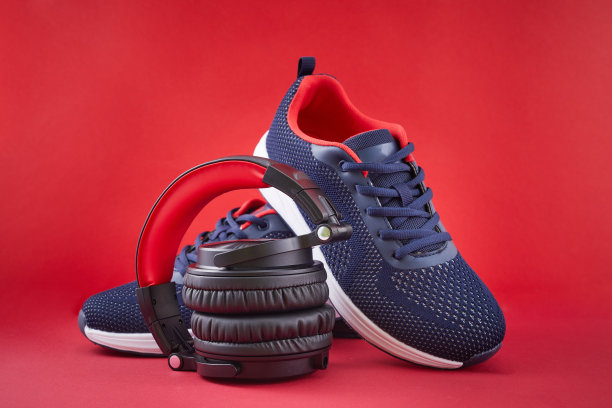 蓝色运动鞋和耳机，红色背景。体育和音乐的概念。图片下载