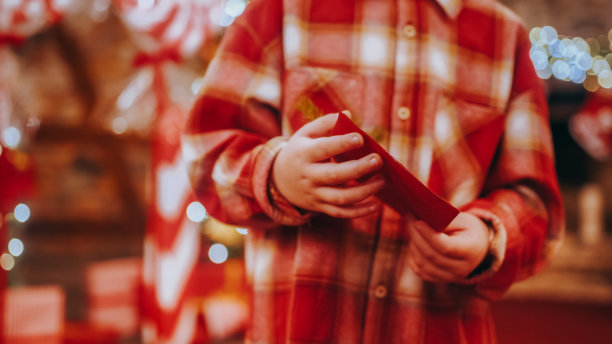 一个面目全非的孩子手里拿着一封装饰好的写给圣诞老人的信图片下载