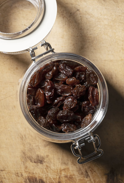玻璃瓶里的葡萄干，背景是古老的木头。图片下载