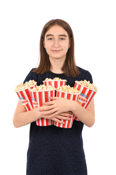 一个美丽的女孩的肖像拿着一桶爆米花站在白色。图片下载