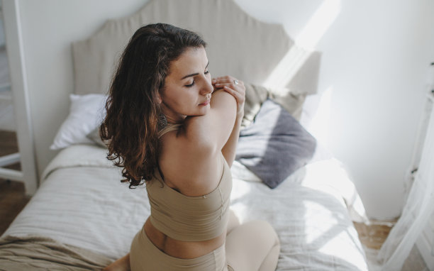 女孩在家里的床上做瑜伽，做关节伸展图片下载