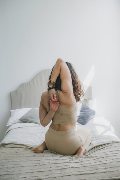 一个小女孩正在做瑜伽伸展，她的手臂交叉在背后图片下载