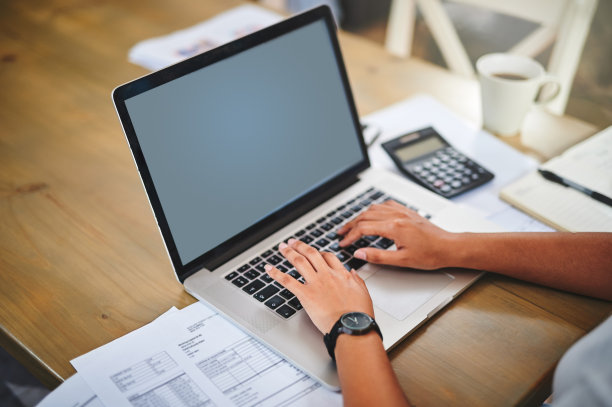 一个不知名的女人在家里的桌子上用笔记本电脑图片下载