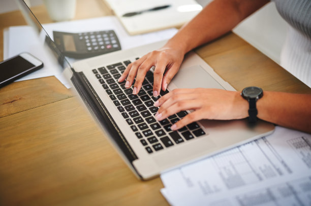 一个不知名的女人在家里的桌子上用笔记本电脑图片下载