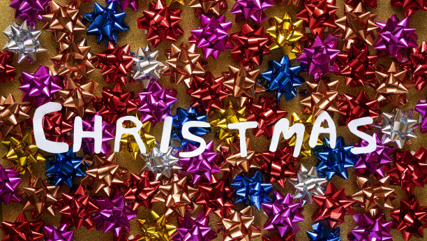 圣诞节标题与单词圣诞节写在白色大写字母的背景上满是五颜六色的蝴蝶结图片下载