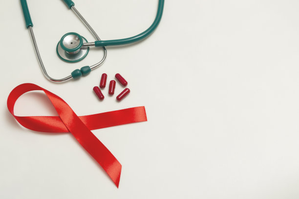 12月世界艾滋病日的医学概念。红色的丝带，绿色的医用听诊器，白色背景上红色的治疗药丸或维生素。关闭复制空间图片下载