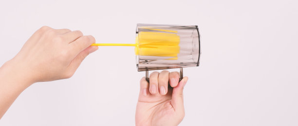 清洁和洗碗的概念。白色背景上的男子洗手酒杯。用柔软的黄色海绵棒清洗饮用玻璃。用海绵刷清洗杯子。新冠肺炎时代的消毒卫生图片下载