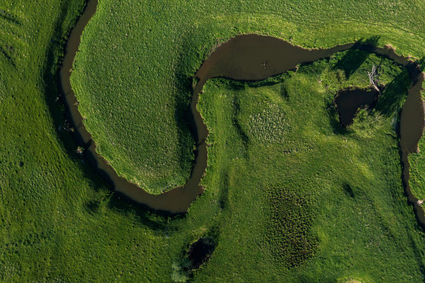 绿色田野中蜿蜒河流的空中景观，从无人机俯瞰美丽的自然纹理图片下载