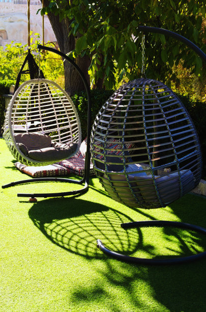 在阳光明媚的日子里，两张带有棕色枕头的现代秋千椅的详细视图放在房子的阳台上图片下载