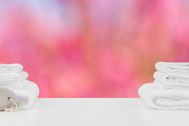堆叠在桌上的白色水疗浴巾在模糊的背景图片下载