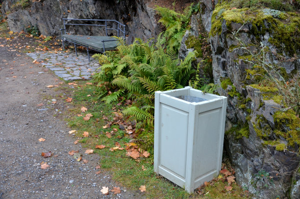 用水平木板砌成的花园房子。在绿色屋顶和攀缘植物和蕨类植物的顶部。浅蓝色的长椅和木制垃圾桶在公园，花园桑拿，花园棚子隐藏图片下载