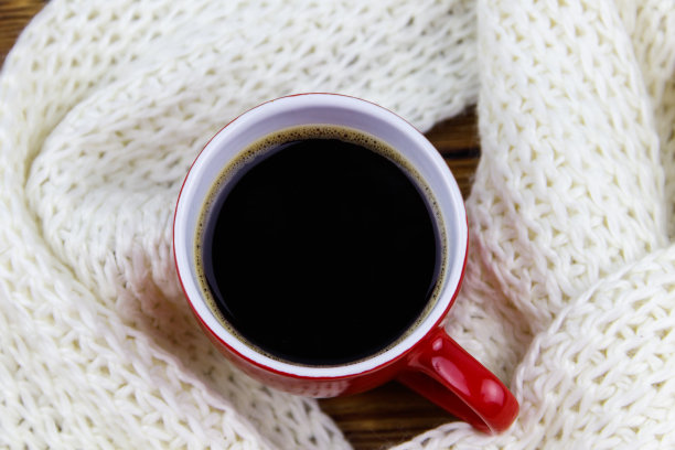 一杯咖啡，围着白色的针织围巾。前视图。冬天舒适的概念图片下载