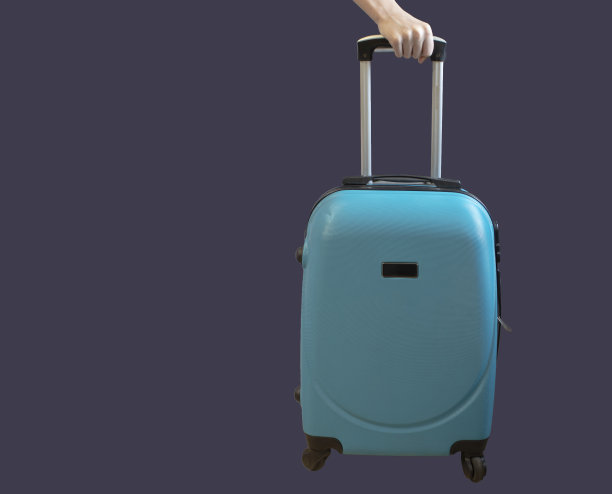 紫色背景上有轮子的手提箱。旅行，对新地方的印象。图片下载